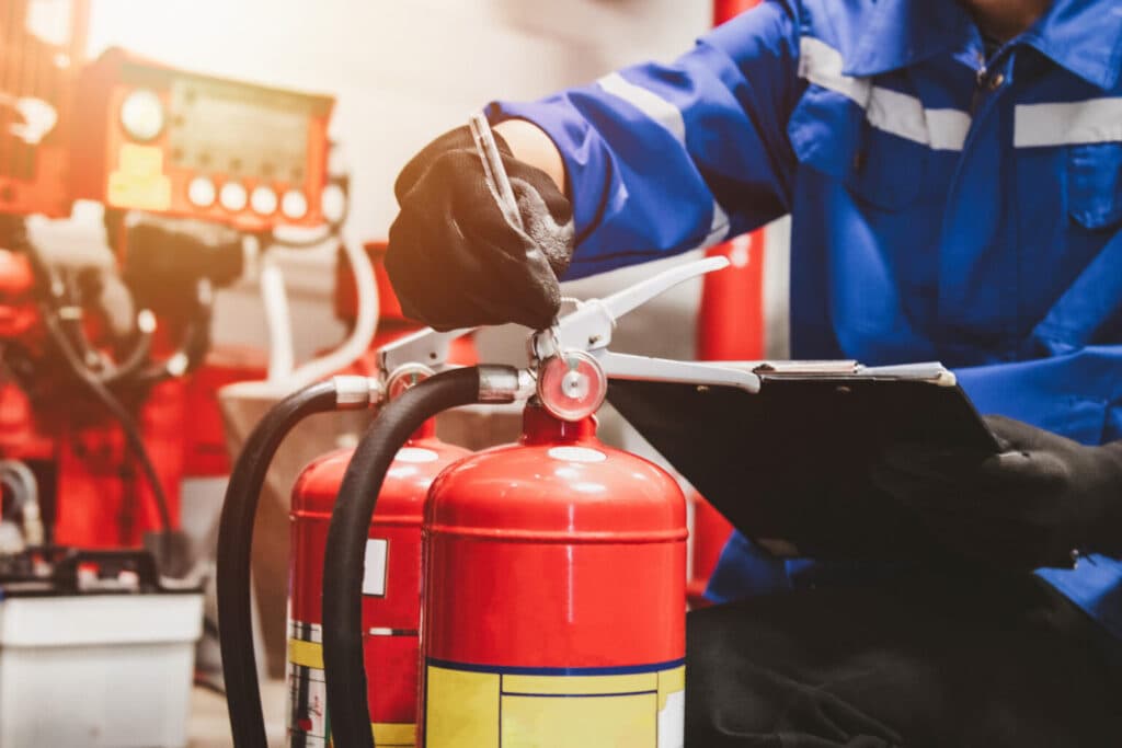 Expert en sécurité incendie réalisant un audit et un contrôle de conformité SSI sur plan avec extincteur.